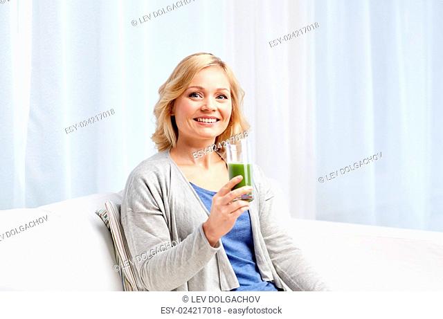 healthy eating, vegetarian food, dieting, detox and people concept - smiling middle aged woman drinking green fresh vegetable juice or smoothie from glass at...