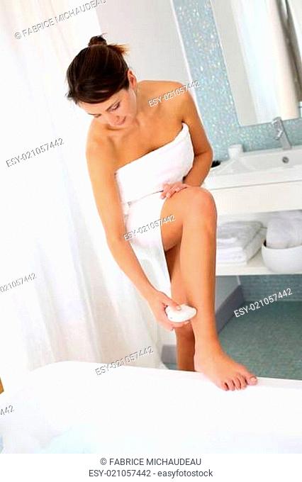 Woman shaving her legs in bathroom