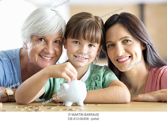 Three generations of women filling piggy bank