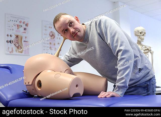PRODUCTION - 23 February 2022, North Rhine-Westphalia, Bielefeld: Jonas Küppers, male midwife, stands in a posed situation with a pinard tube on a phantom of a...