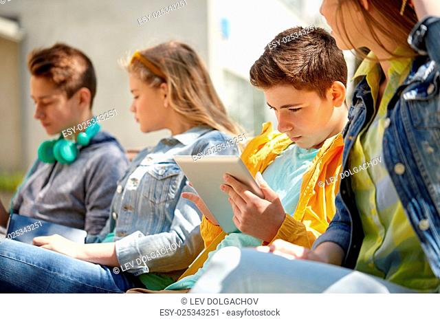 technology, internet and people concept - group of teenage friends or high school students with tablet pc computer outdoors