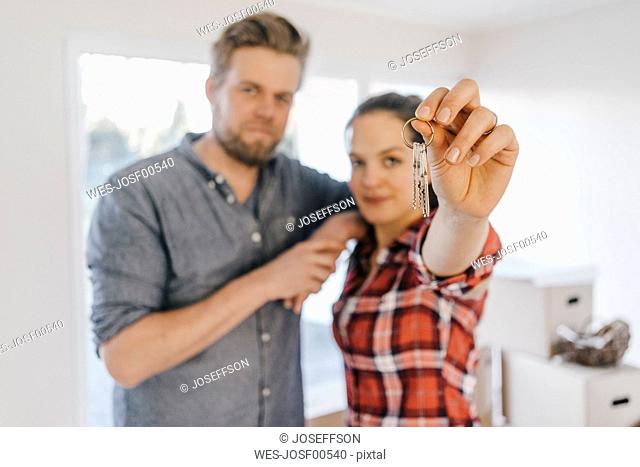 Couple moving house, woman holding keys of new home