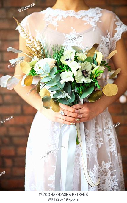 Unusual wedding bouquet in retro style at hands of a bride