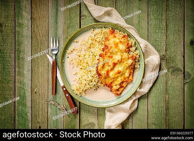delicious tasty grilled chicken with ananas and cheese with rice in a green elegant porcelain plate, on the old, green wood table