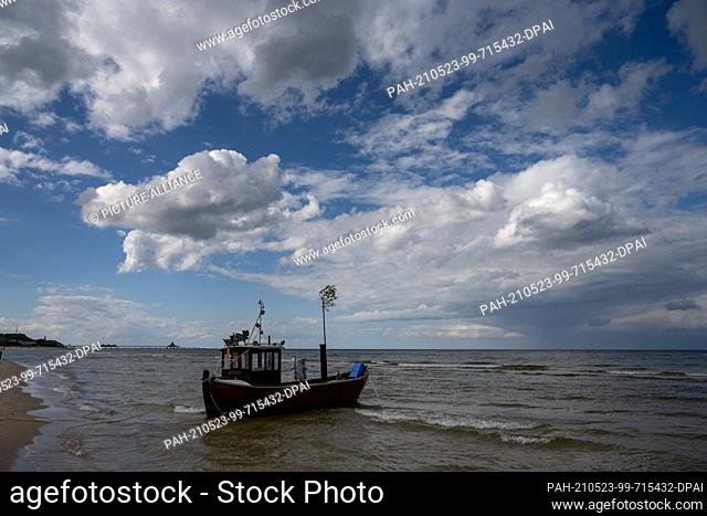 23 May 2021, Mecklenburg-Western Pomerania, Ahlbeck: Waves crash in front of a fishing boat on the Baltic Sea beach of the Baltic resort Ahlbeck on the island...