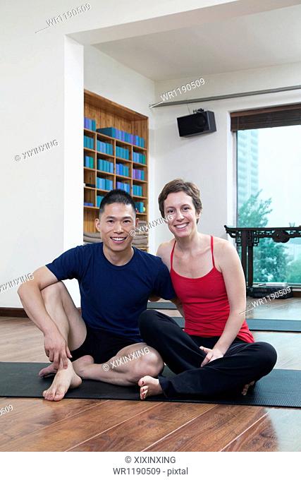 Two people relaxing and looking at camera in a yoga studio