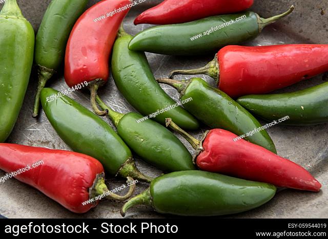 A close up studio photo of red and green chili peppers on a platter
