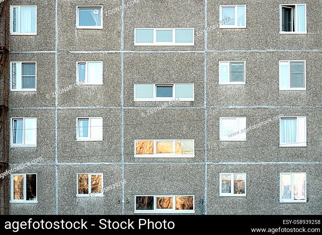 Facade of a grey multi-storey soviet panel building. Russian old urban residential houses with windows. Typical russian neighborhood