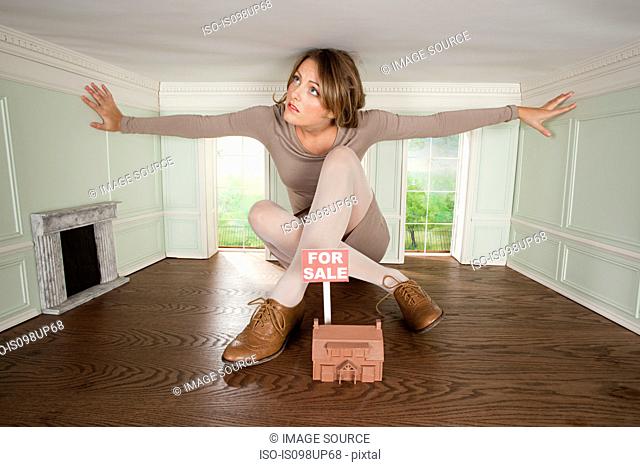 Young woman in small house with model of house for sale
