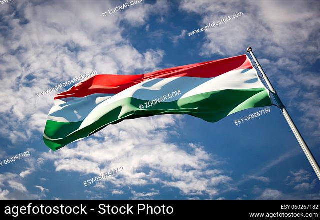 Beautiful national state flag of Hungary fluttering at sky background. Low angle close-up Hungary flag 3D artwork