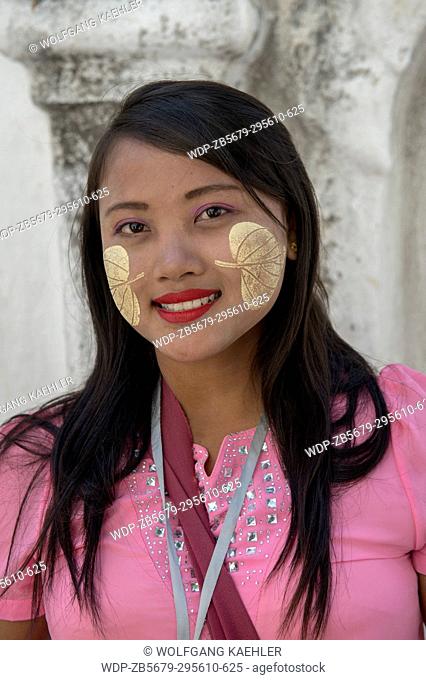 Portrait of a young woman with a decorative paste made out of the Thanaka tree on her face at the Kuthodaw Pagoda on Mandalay Hill, Mandalay, Myanmar