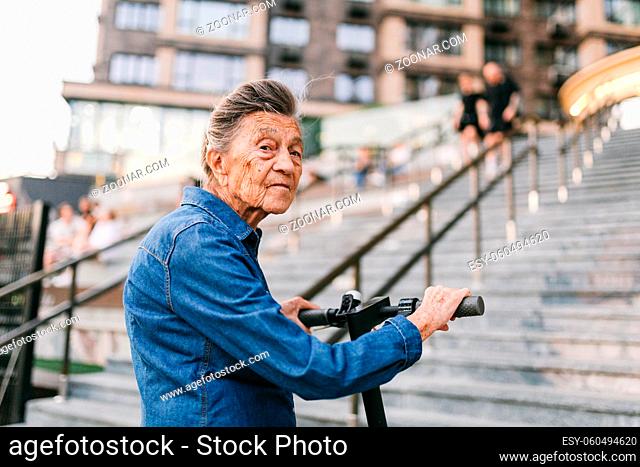 Active old woman riding electric scooter. Retired lady uses environmentally friendly city vehicle. Granny very old with gray hair, active and progressive