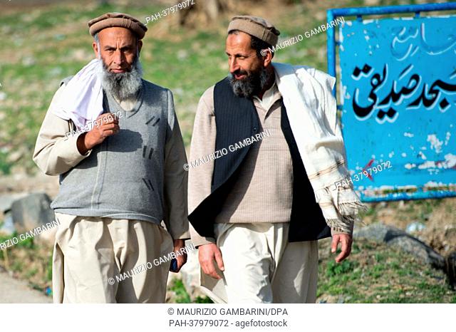 Two men wearing Pakols, the regionally typical round warm cap, walk through Khwaza Khela in the Swat valley, Pakistan, 07 March 2013