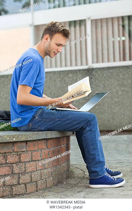 Content handsome student sitting on wall studying