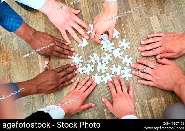 Viele Hände von Geschäftsleuten spielen mit Puzzle als Teamwork Konzept