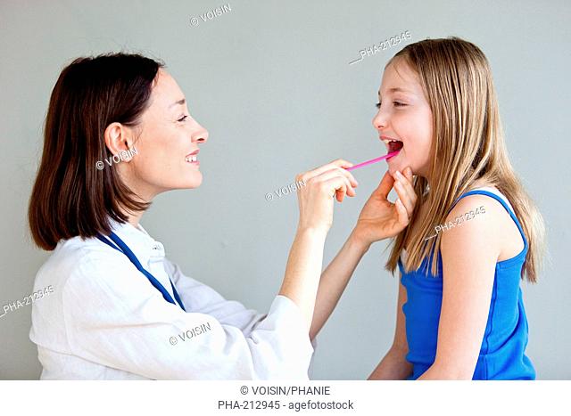 A pediatrician examines the throat of a 9 years old child