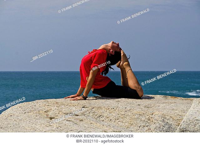 Woman in a yoga position, Bhujangasana, by the sea in Kanyakumari, Tamil Nadu, India, Asia