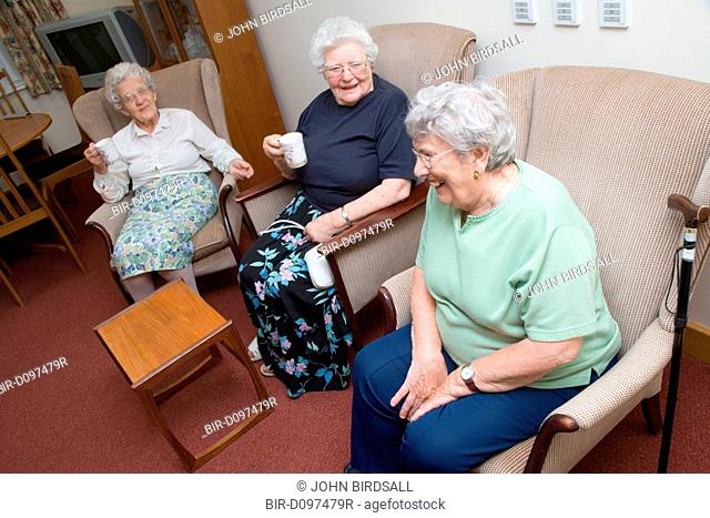 A group of older ladies enjoying a coffee morning in the communal lounge of a warden aided home