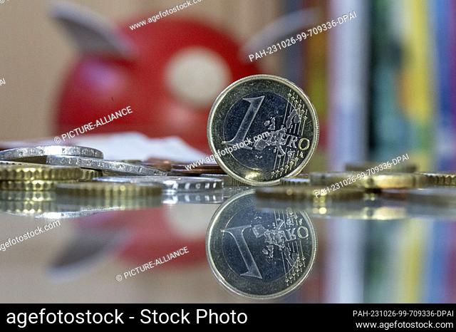 ILLUSTRATION - 23 October 2023, Saxony, Leipzig: A 1 euro coin stands on a table in front of a piggy bank. October 30, 2023 is World Savings Day