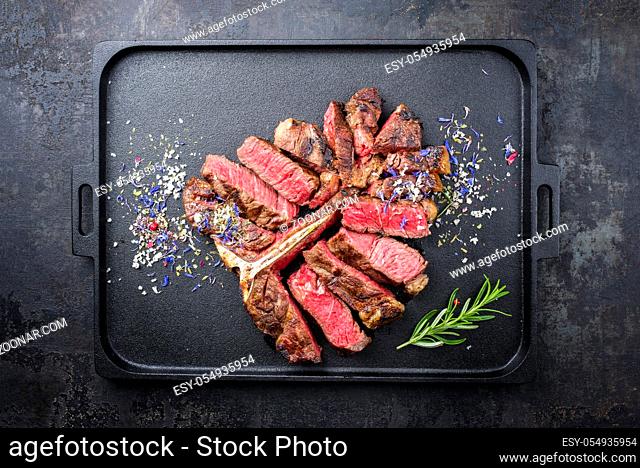 Traditional barbecue dry aged wagyu porterhouse steak sliced with herb and spice as top view on a modern design tray