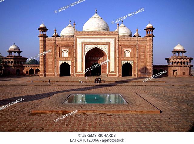 TAJ MAHAL. MOSQUE. RED STONE BUILDING WITH 3 WHITE MARBLE DOMES. WATER POOL IN FOREGROUND. MUGHAL STYLE