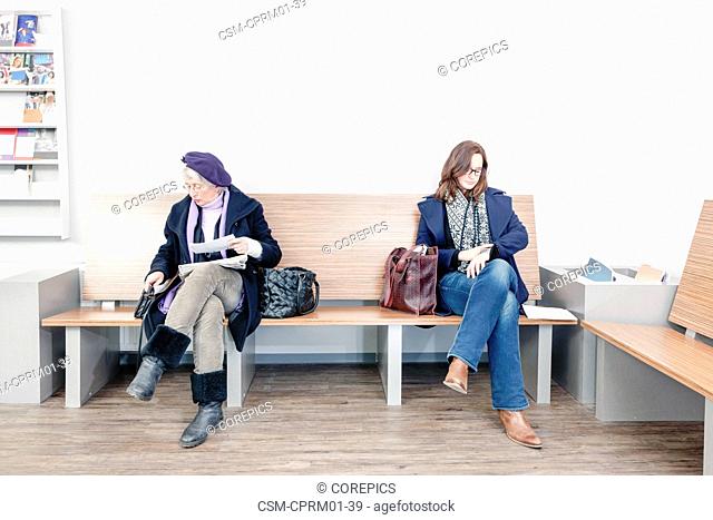 Two women waiting impatiently in the waiting room of a medical practice