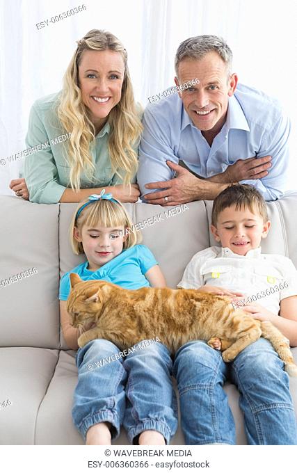 Cute family relaxing together on the couch with their cat