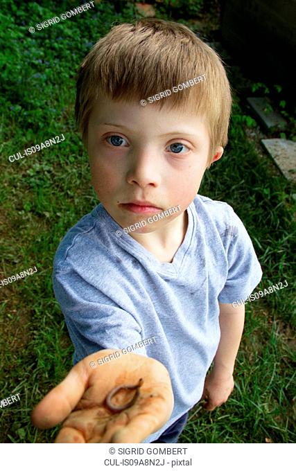 Close up portrait of boy with a worm in his hand