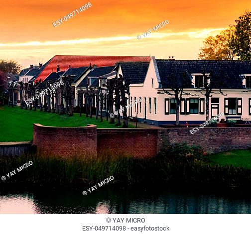 view on some modern houses with water and grass at sunset in the city Leerdam the Netherlands, typical dutch neighborhood