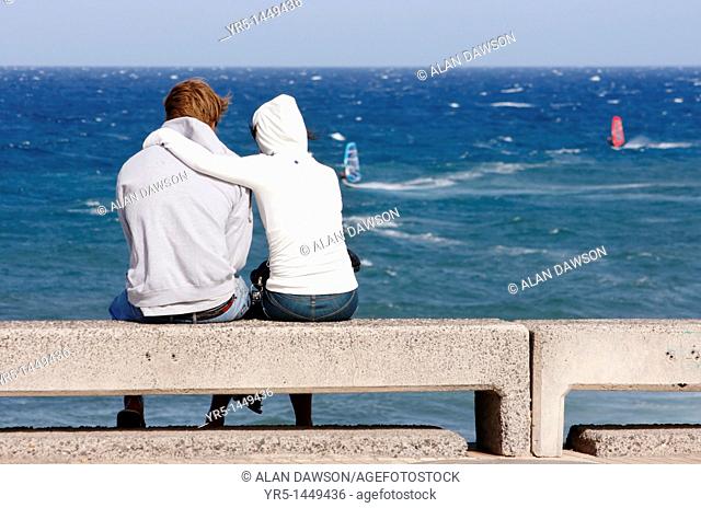 Young couple watching windsurfers at Pozo Izquierdo on Gran Canaria, Canary Islands, Spain