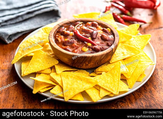 Chili con carne and tortilla chips on plate. Mexican food with beans in wooden bowl