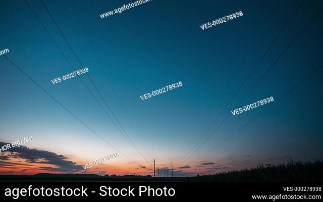 4K Sunset Sky Transition To Dark Night Starry Sky With Glowing Stars And Meteoric Track Trail. Landscape with Electrical Power Lines In Starry Sky Background...