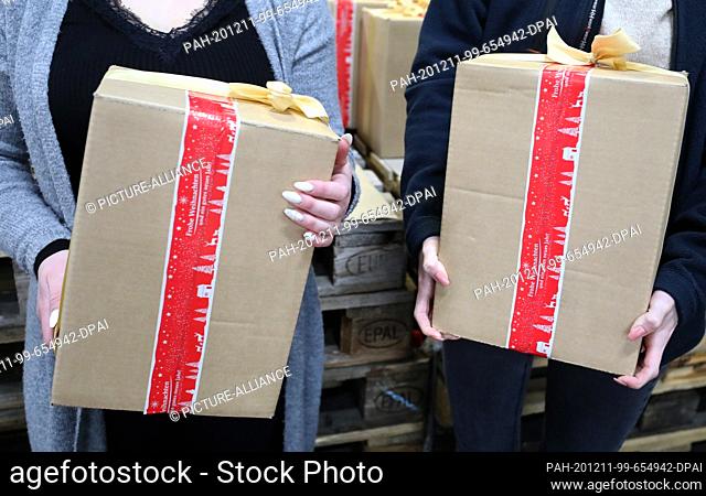 11 December 2020, Mecklenburg-Western Pomerania, Rostock: Dina Gerion (l) and Sophia Driemel and Dina Gerion are packing Christmas parcels for seafarers at the...