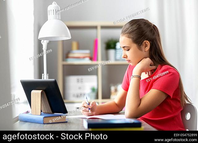 teenage student girl writing to notebook at home