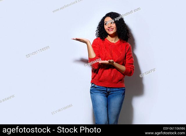 Happy young woman in red sweater pointing away