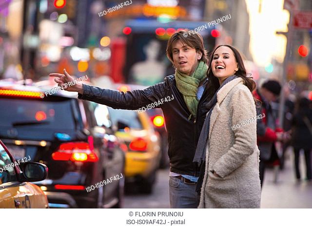 Young tourist couple hailing a cab, New York City, USA
