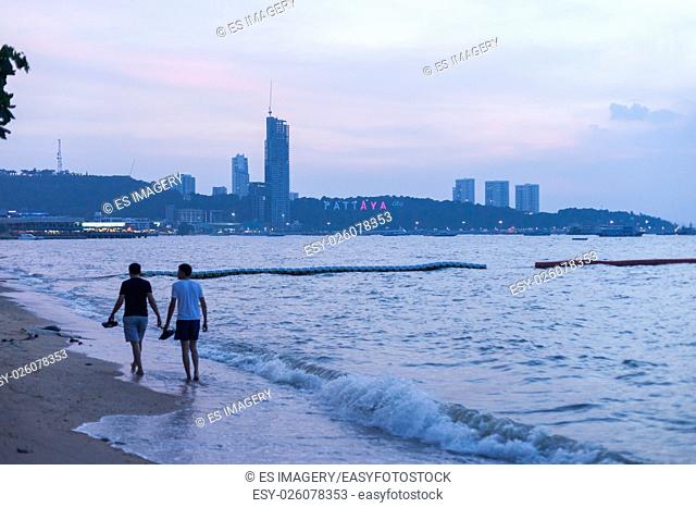 Two men walk down the beach in Pattaya, Thailand