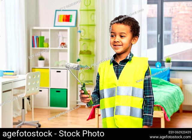 boy in safety vest with paint roller at home