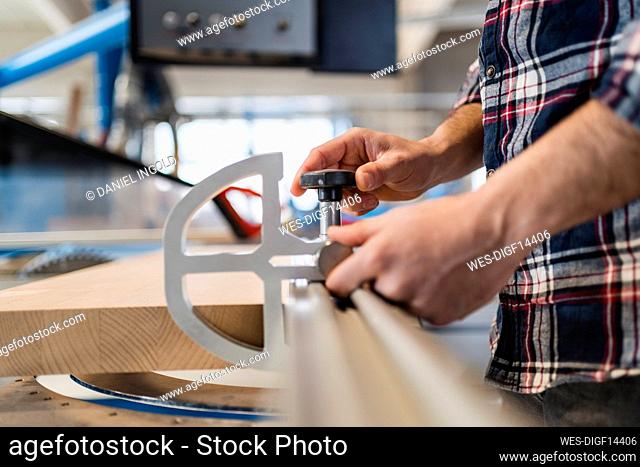 Male manual worker adjusting tool on plank while standing at factory