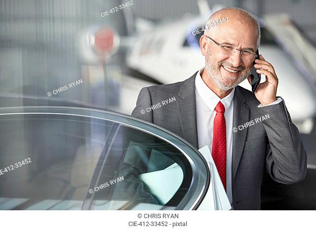 Smiling businessman talking on cell phone in airplane hangar