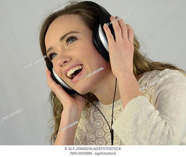 Young happy woman listening to music in headphones