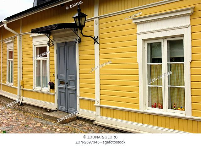 Ockergelbe Fassade eines typischen finnischen Blockhauses mit Fenstern und Eingangstür in der Altstadt von Porvoo, Finnland / Ocher-yellowish fassade of a...
