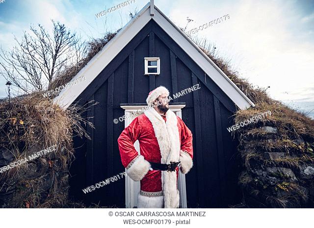 Iceland, Santa Claus standing in front of cabin looking at distance