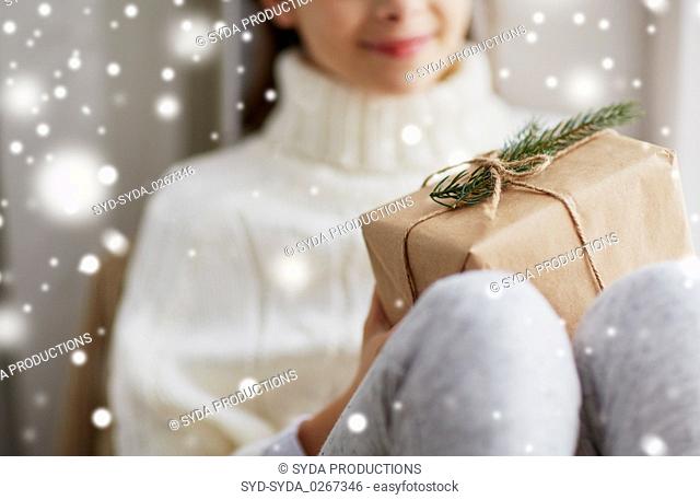 girl with christmas gift sitting on sill at home