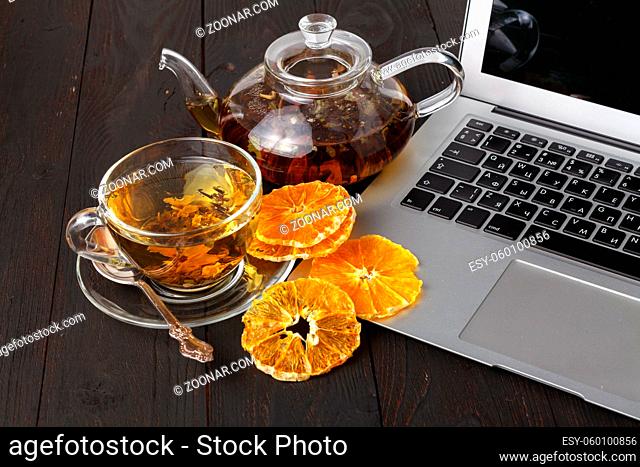 Teapot with black tea, roses, oranges and grapefruit on light background