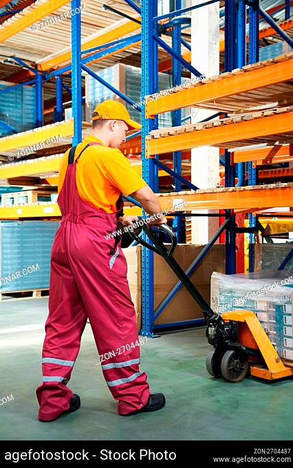 worker with fork pallet truck stacker in warehouse loading furniture panels
