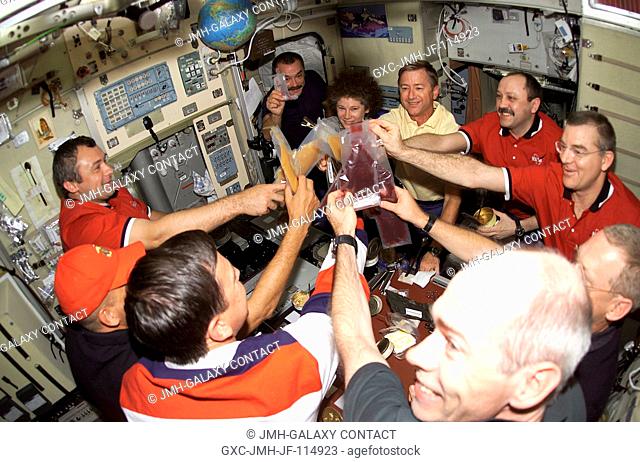 Beverages are held high in a toast onboard the Zvezda Service Module of the International Space Station (ISS) as the astronauts and cosmonauts of STS-105 and...