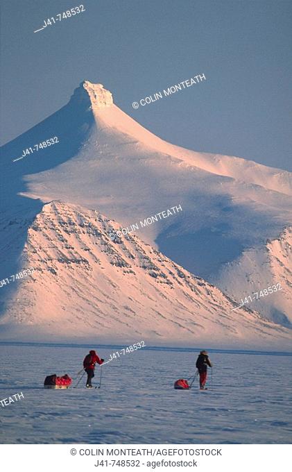 Ski tourers hauling sledges on spring traverse Ny Alesund to Longyearbyen Spitsbergen Island Svalbard Norwegian Arctic