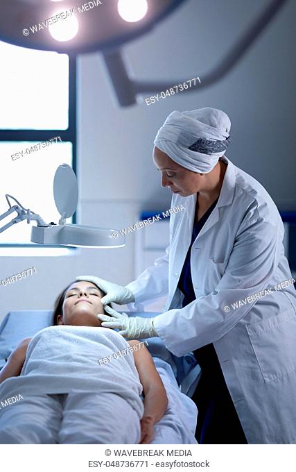 Female surgeon examining patient during plastic surgery
