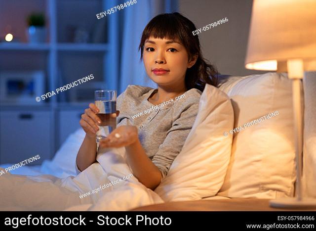stressed asian woman taking medicine at night